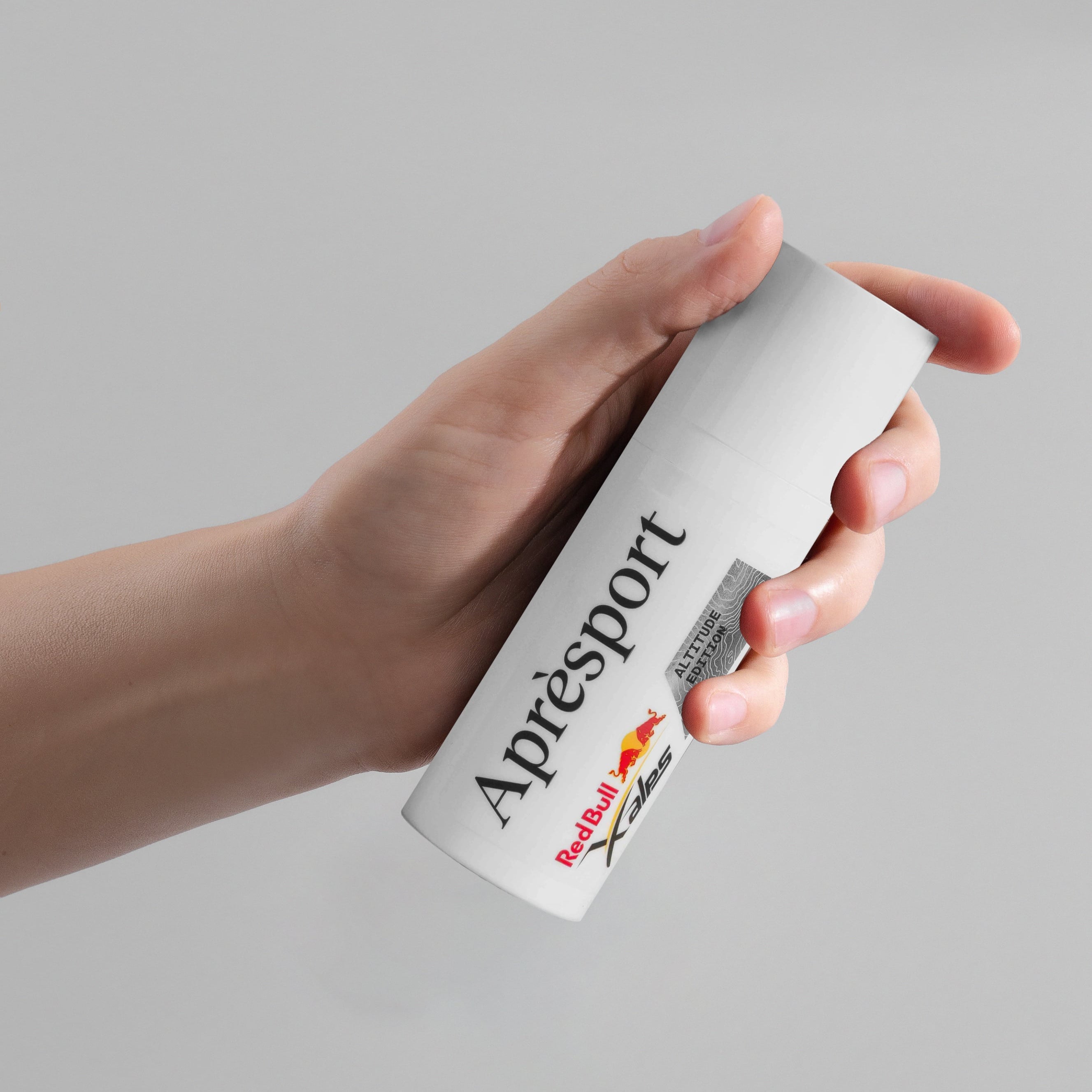 Hand holding a can of Red Bull Apresport on a gray background